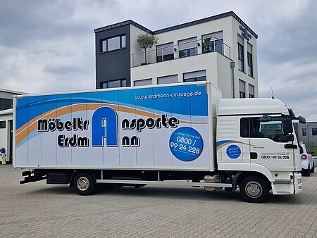 Ein weißer LKW. An der Seite des Fahrzeugs ist das Möbeltransport Erdmann Logo