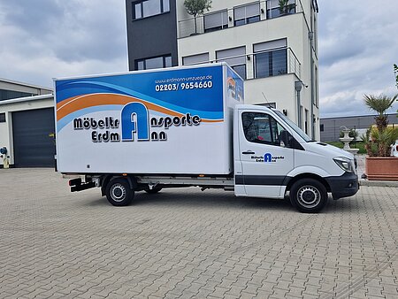 Ein weißes Transportfahrzeig. An der Seite des Fahrzeugs ist das Möbeltransport Erdmann Logo abgebildet